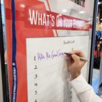 Photo of a hand holding a dry-erase marker writing on GF 111 EraseMark 2.0 Mil dry erase clear laminate