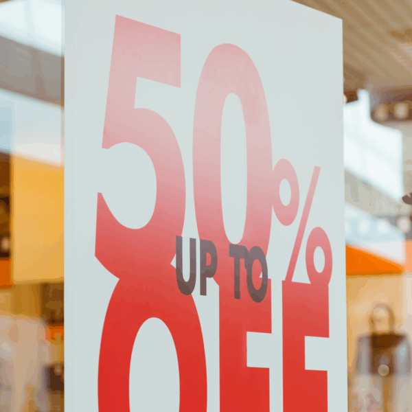 A photo of a white sign hanging in a store window that reads, "Up to" in small, black, all-caps text and, "50% OFF," in large, red, all-caps text. Printed on GF 204.