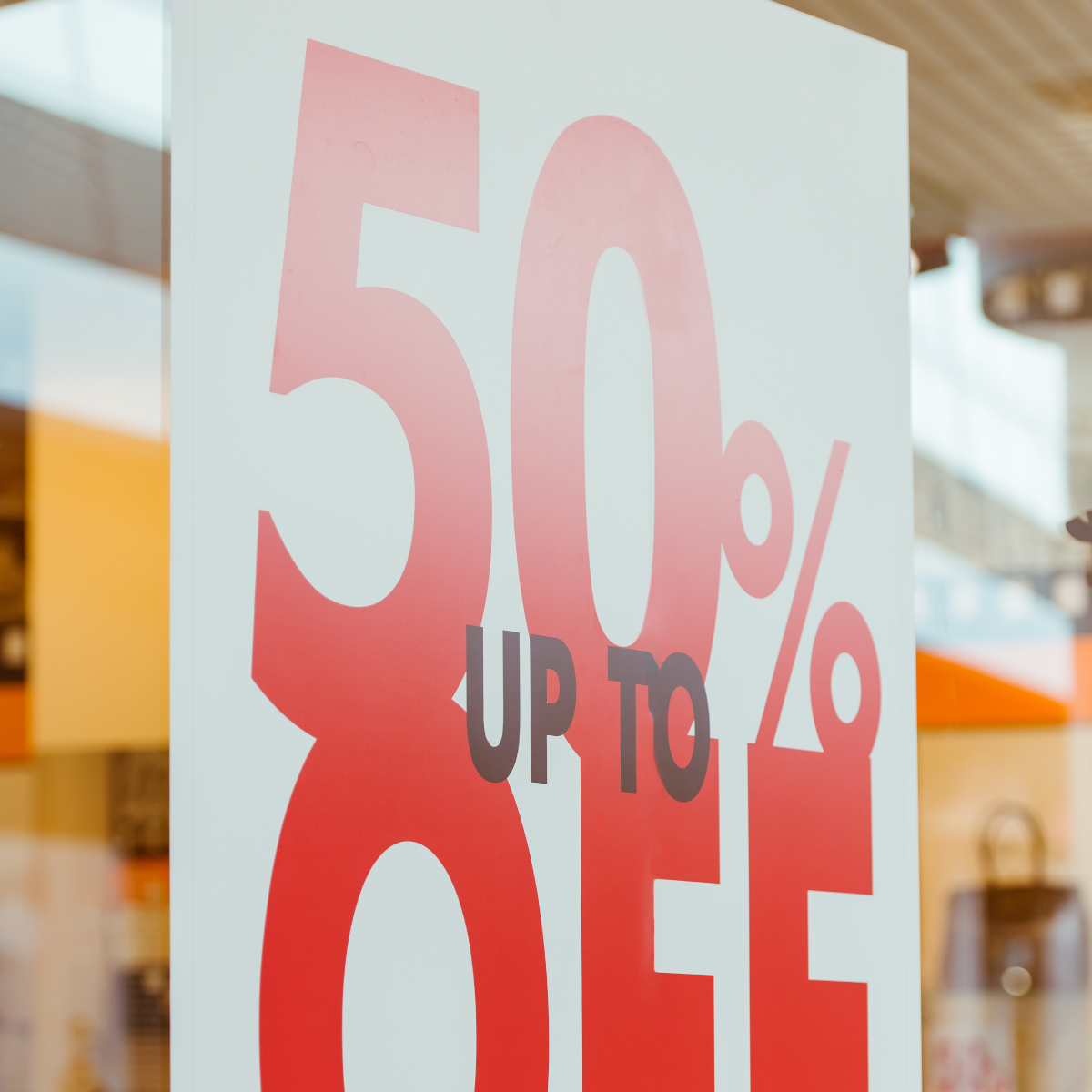 204_Image_square A photo of a white sign hanging in a store window that reads, "Up to" in small, black, all-caps text and, "50% OFF," in large, red, all-caps text. Printed on GF 204.