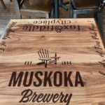 A photo of a wooden table with black text that says, "Muskoka Brewery." The text was printed on GF 205 and applied to the table.