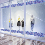 A photo of mannequins standing in the window of a store at a shopping mall. There are blue and purple flowers printed on GF 206 adhered to the window.