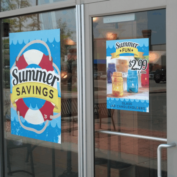 A photo of a glass door and large window at the front of a store. There are two blue static cling signs attached to the windows. One says, " Summer Savings" in black text on top of a live preserver, the other has a photo of some beverages for $2.99. The static clings are printed on GF 208.