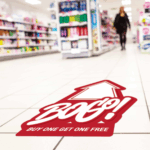 Photo of a floor graphic printed on GF 210 on a tiled floor in a store that is red with a white arrow and white text that reads, "BOGO! Buy One Get One."