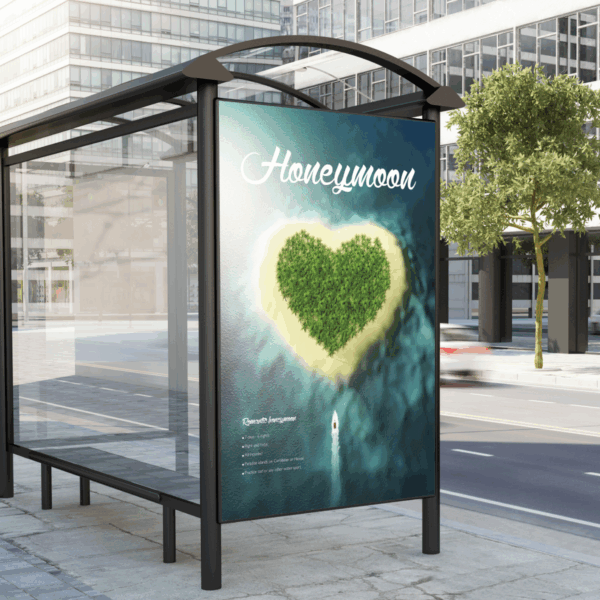A photo of a bus stop in a city comprised of clear windows and a black frame. On the side of the bus stop is an advertisement that is a photo of a heart-shaped tropical island in the ocean with the word, "Honeymoon," written across the top in white script text. The advertisement was printed on GF 222.
