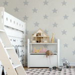 A photo of a child's bedream containing a white, low-loft bed with crawlspace underneath, and a small white shelf with a dollhouse on top. The wallpaper is white with grey stars. The wallpaper was printed on GF 229.