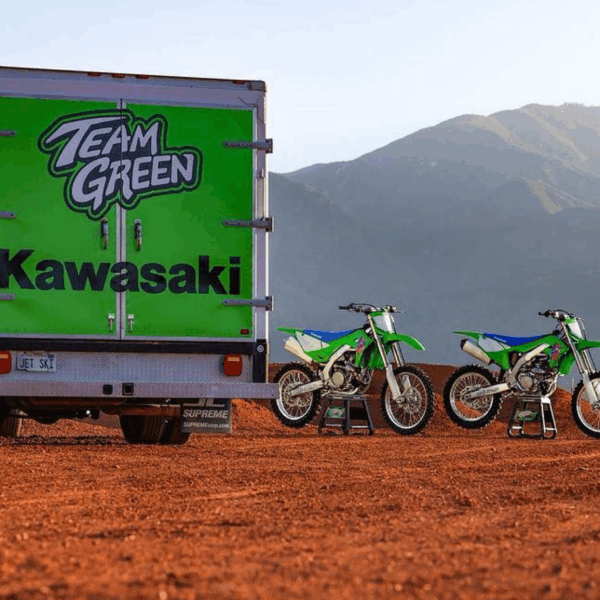 A photo of what looks to be the desert of the Southwestern USA. There is a large hill in the back. There are green dirt bikes, along with a green box truck. On the truck is a graphic that says, "Team Green," in large, white all-caps text outlined in black. Beneath that is the Kawasaki logo in black. The graphics on the truck were printed on GF 230.