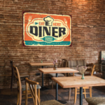 A phot of the inside of a restaurant. There are light wooden tables and chairs. There is a graphic on the wall that says, "Diner," in large, black text. The rest of the graphic is off-white, orange, and blue. It was printed on GF 285.