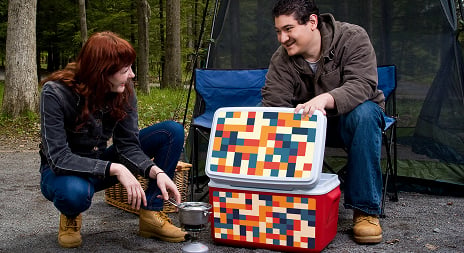 A man and a woman on a picnic in the woods. There is a multi-colored checker printe on a red and white cooler. The checker printed is printed on Arlon DPF 8200