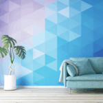 Photo of a living room. The floor is a light wood, there is a white base runner, and a large green plant in a white pot. There is a light green couch with pillows the same color and a white blanket. The wall is comprised of purple and blue triangles in different shades. The wallpaper is printed on GF 226HTR.