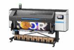 A photo of the HP Latex 830 from the front. The printer is angled slightly to the left. There is paper loaded with a white O and R visible with daisies and marigolds.