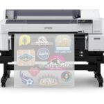Epson SureColor G6070 35 DTFilm Printer with a roll of clear film coming out. Various sports logos are printed on the film.