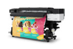 A photo of an Epson SureColor S7170 printer at an angle with a large printout in the colors yellow, green, and pink, with ice cream.