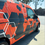 Image of a van with Arlon Omni Cast Wrap applied having black, orange, and white octagons printed on it.