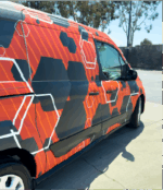 Image of a van with Arlon Omni Cast Wrap applied having black, orange, and white octagons printed on it.