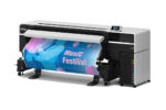 A photo of right angle view of the Epson SureColor S8170 64″ Printer with a blue and pink print coming out with the words "music festival."