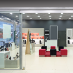 A photo of a shoe store. There is a off-white floor, white and orange shelves, and black wall, and red seats. Used for the GF 248 listing.