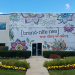 A photo of the outside of a building with a white mural with colorful flowers on it. The mural was printed on GF 260.