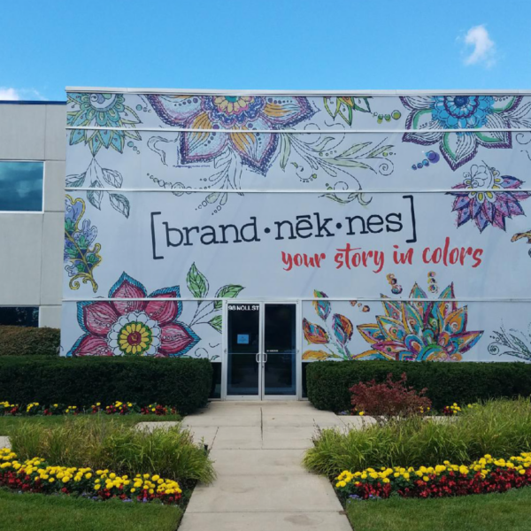 A photo of the outside of a building with a white mural with colorful flowers on it. The mural was printed on GF 260.