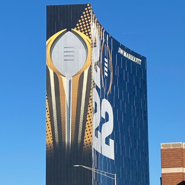 A photo of a tall Marriot hotel. The building appears black, with a gigantic image of an American football trophy in white, silver, and gold on the end of the building, wrapping around with a large white 22 and a simplified outline of a football on the front. The image was printed on GF 270.