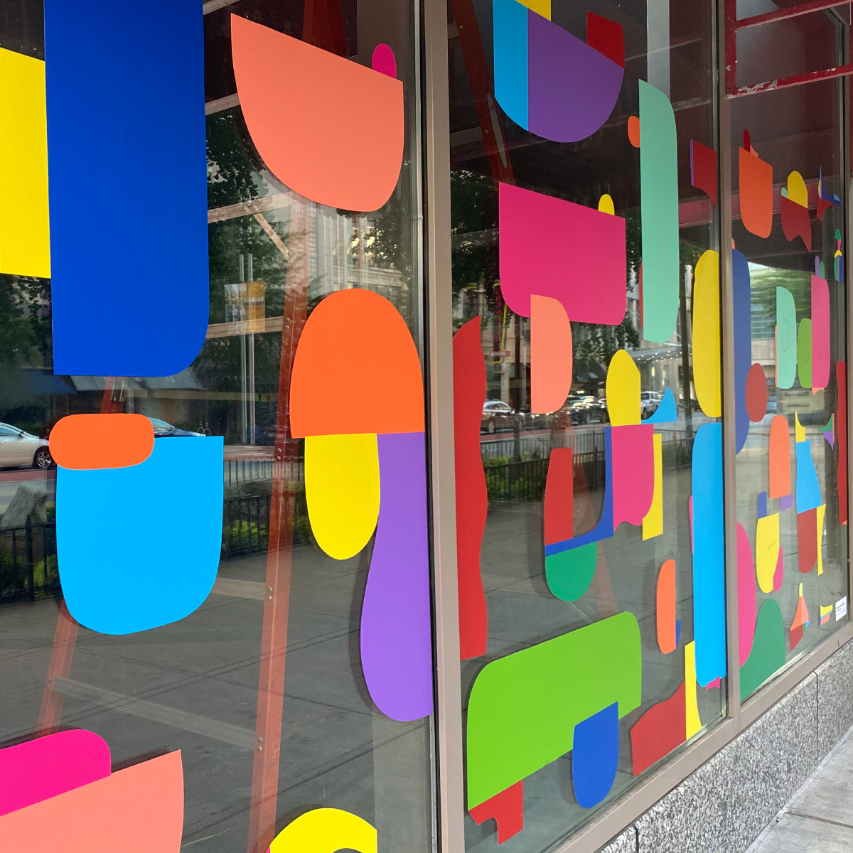 280_WindowMark_Image_square A photo of the front windows of a business. They are covered in random geometric shapes with round corners in colors such as blue, sky blue, orange, yellow, purple, green, and red. The shapes were printed on GF 280.