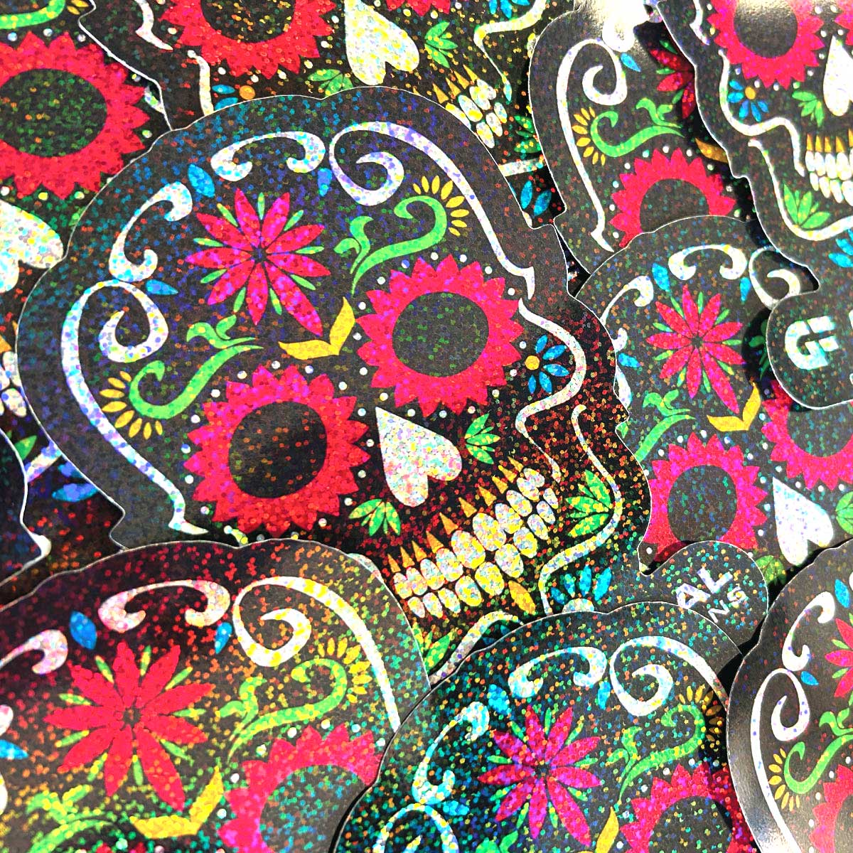 767_Image Photo of sugar skull stickers, black with white, green red, pink, and yellow. Sprinted on GF 767 sparkle holographic.